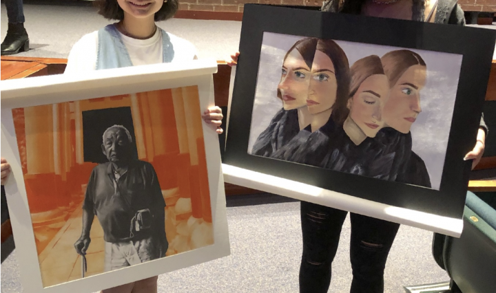Photo of TMI Students Sara Homma and Kristina Samuel displaying their artwork at the Feb. 23 regional Visual Arts Scholastic Event at John Paul Stevens High School.